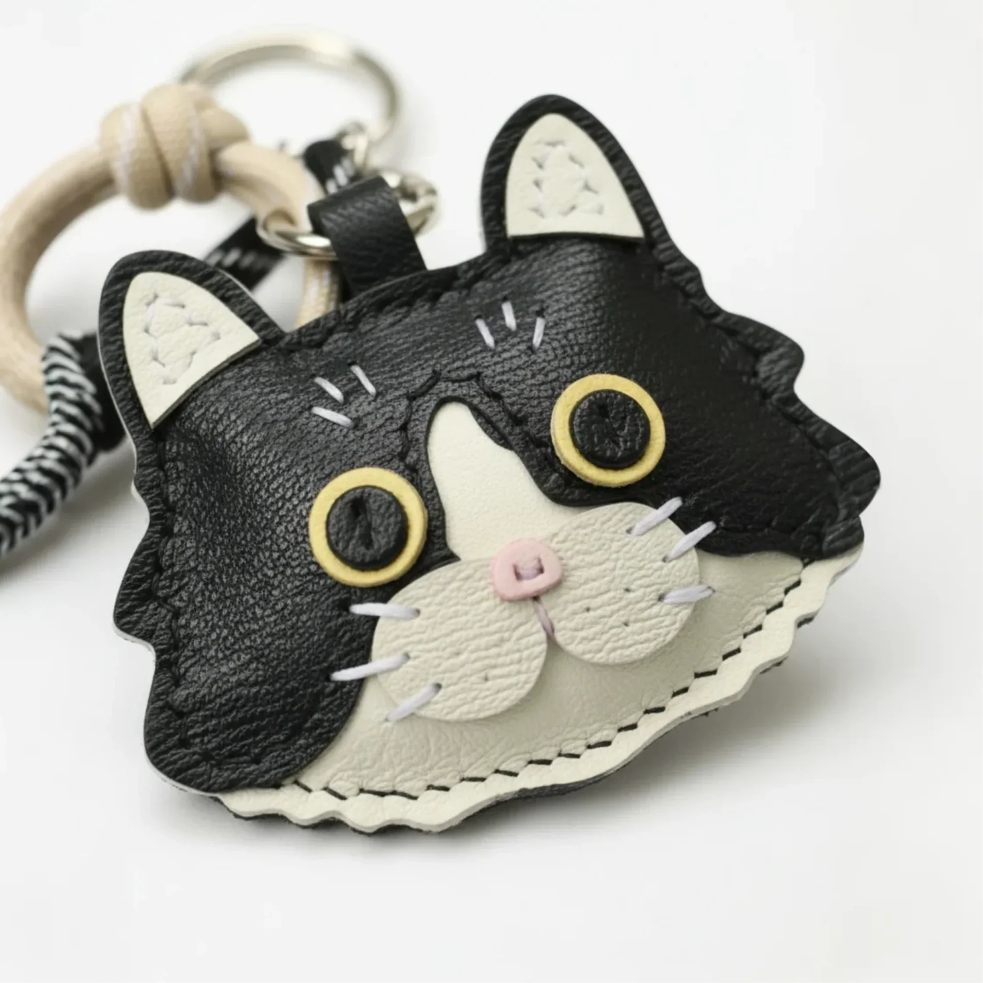 Close-up macro shot of a handmade cat leather keychain, highlighting the fine stitching and layered leather details.