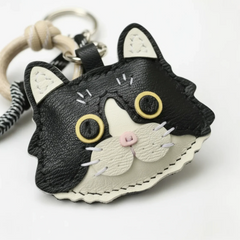 Close-up macro shot of a handmade cat leather keychain, highlighting the fine stitching and layered leather details.