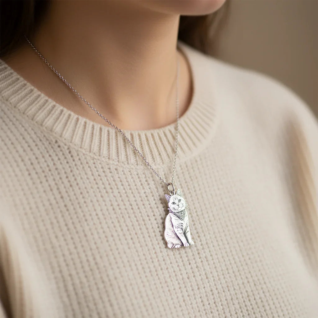 A woman wearing a custom full-body sterling silver cat necklace, personalized from a pet photo, paired with a beige sweater.