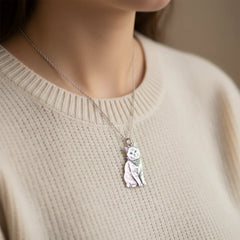 A woman wearing a custom full-body sterling silver cat necklace, personalized from a pet photo, paired with a beige sweater.