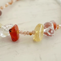 Close-up detail of natural raw crystal jewelry, showing the organic shapes and texture of stones like carnelian, citrine, and clear quartz.