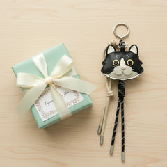 A custom cat leather keychain placed next to a beautiful gift box, making a perfect gift for a pet owner.